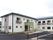 白い外壁の２階建ての建物である。入口部分の外壁や屋根は緑色である。建物の前はアスファルトの駐車場になっている。
