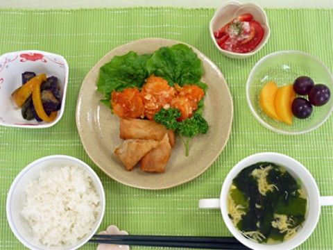 ご飯と、春巻きにサラダを添えた副菜、わかめスープに、果物を添えた献立