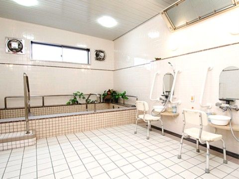 白を基調とした空間。床と浴槽はタイル張りになっている。シャワーの両側には手すりが取り付けられている。