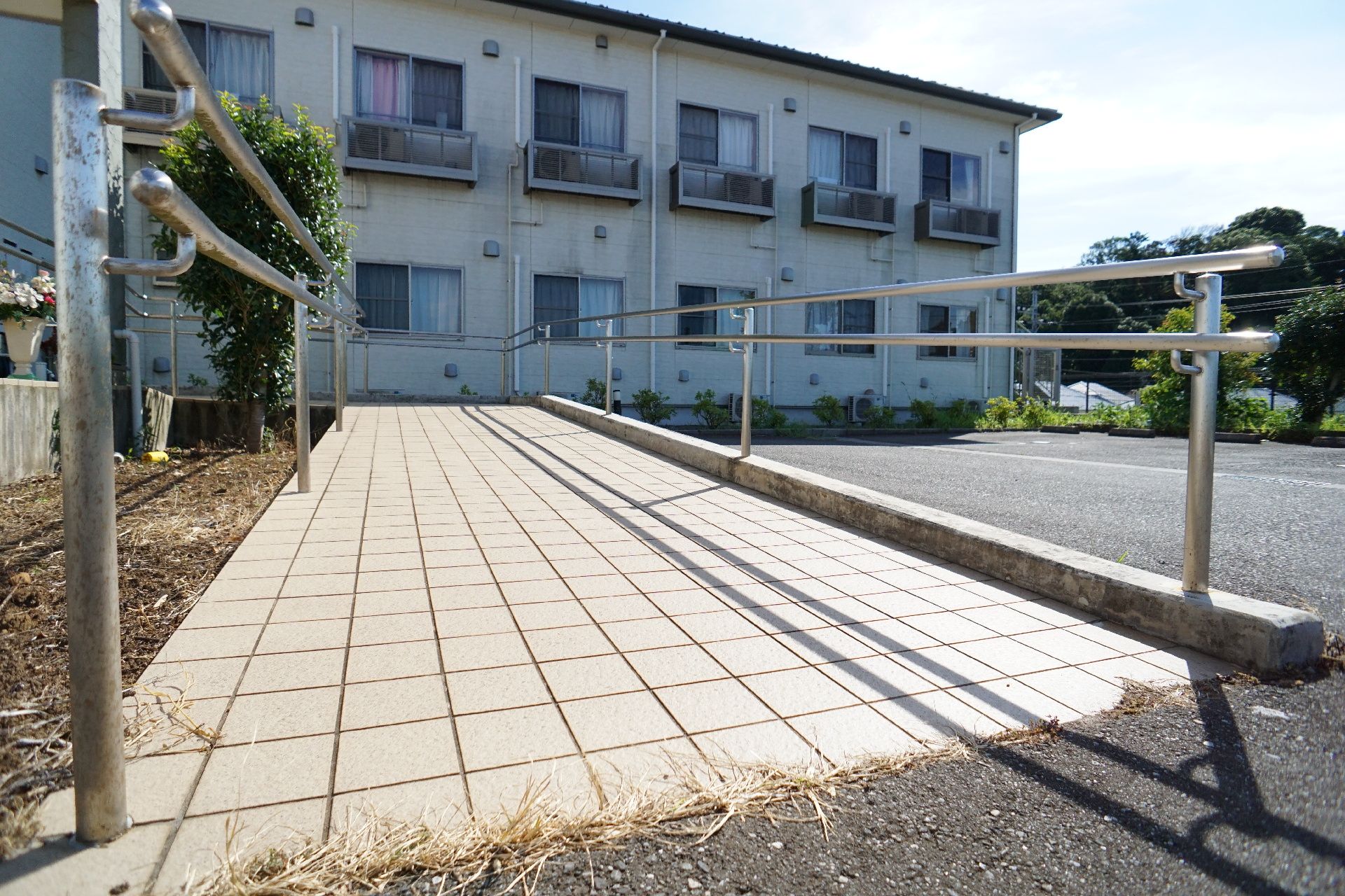 建物の近くに設置されたタイル調の床の手すりが付いたスロープ