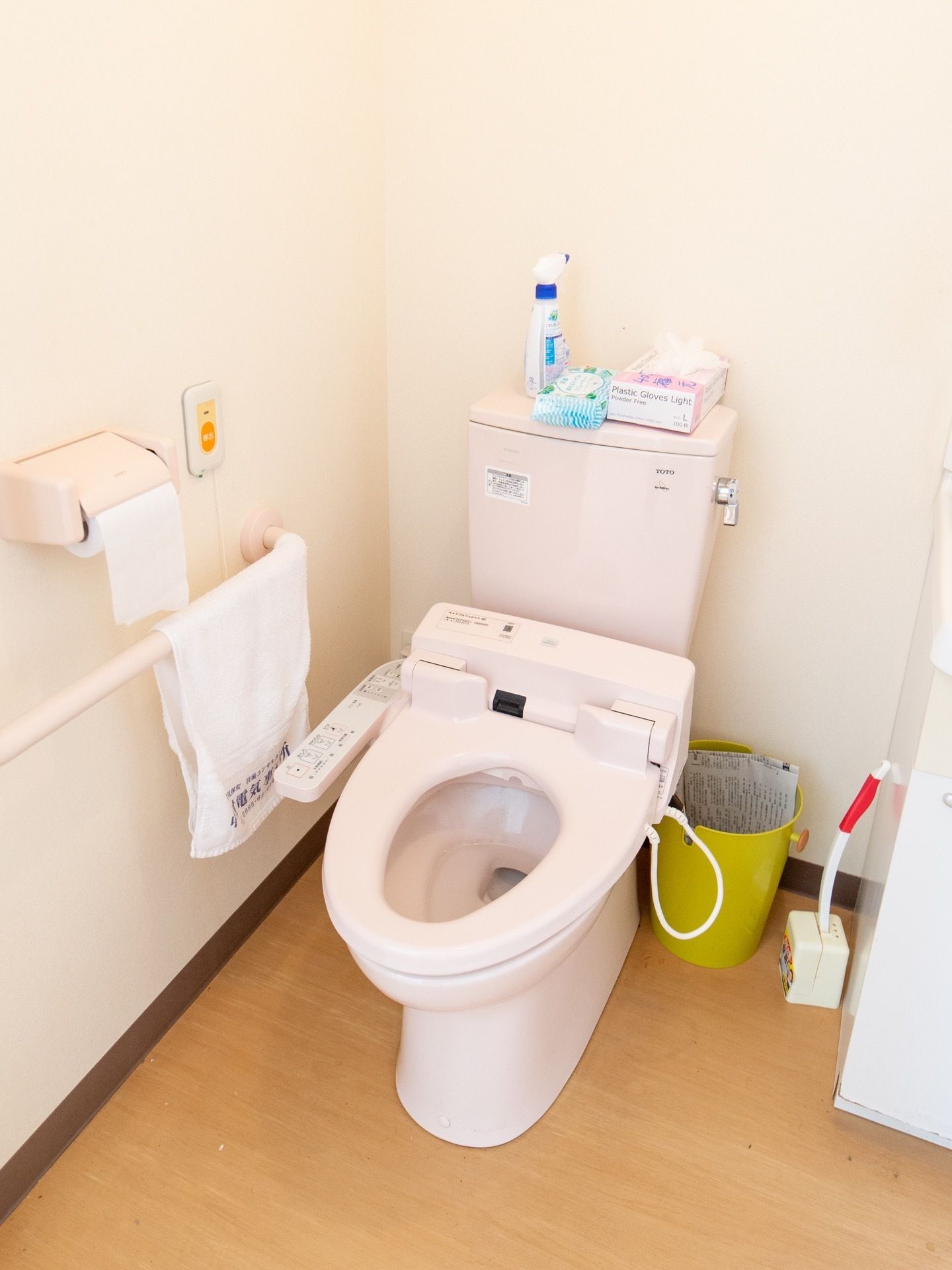 温水洗浄付き暖房便座トイレで、壁には手すりが設置してある。掃除用品がトイレ内に置かれ、呼び出しボタンも完備してある。