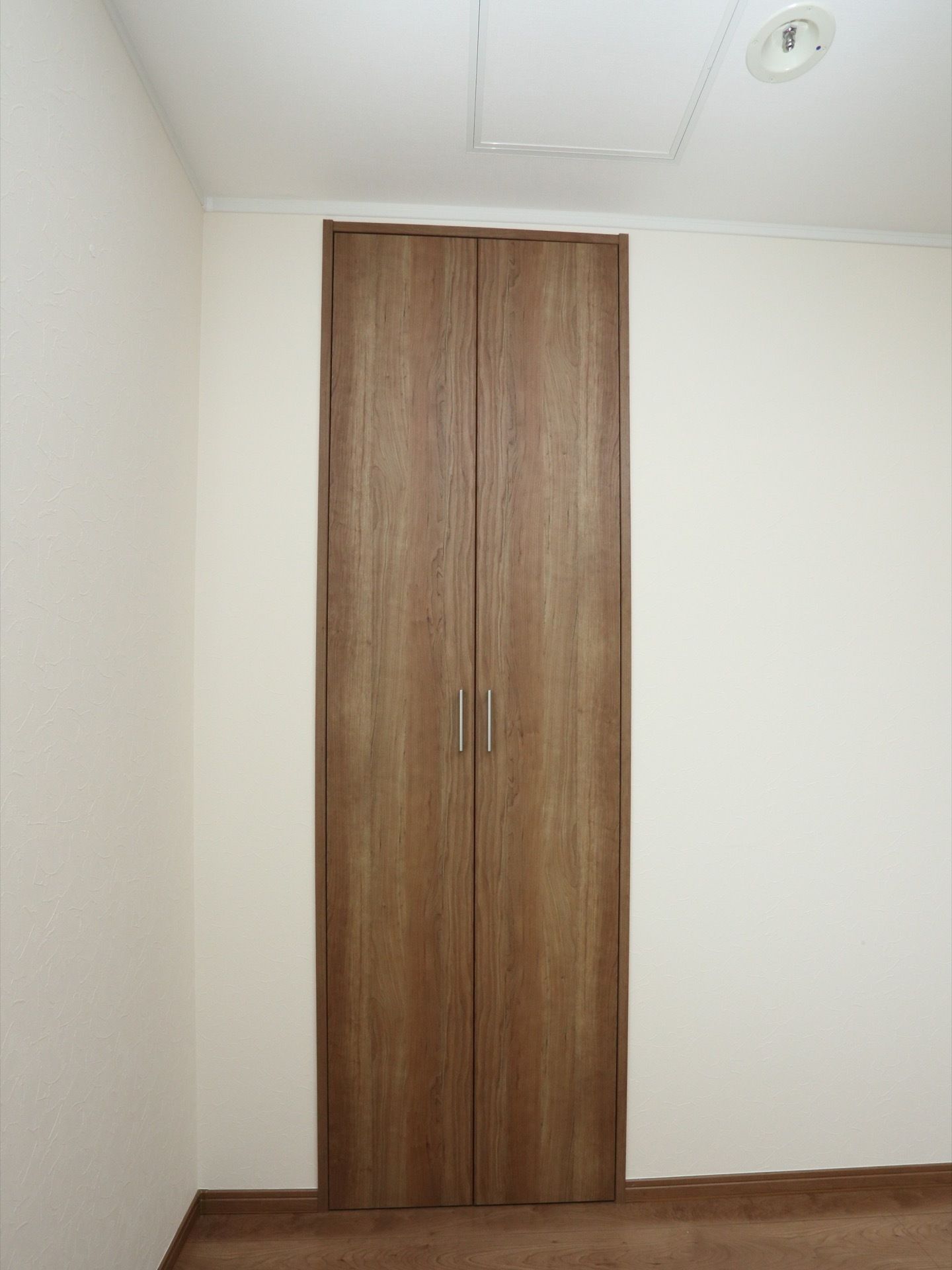 木目調のドアには取っ手がついており、両開きタイプになっている。床も同じ素材のフローリングになっている。