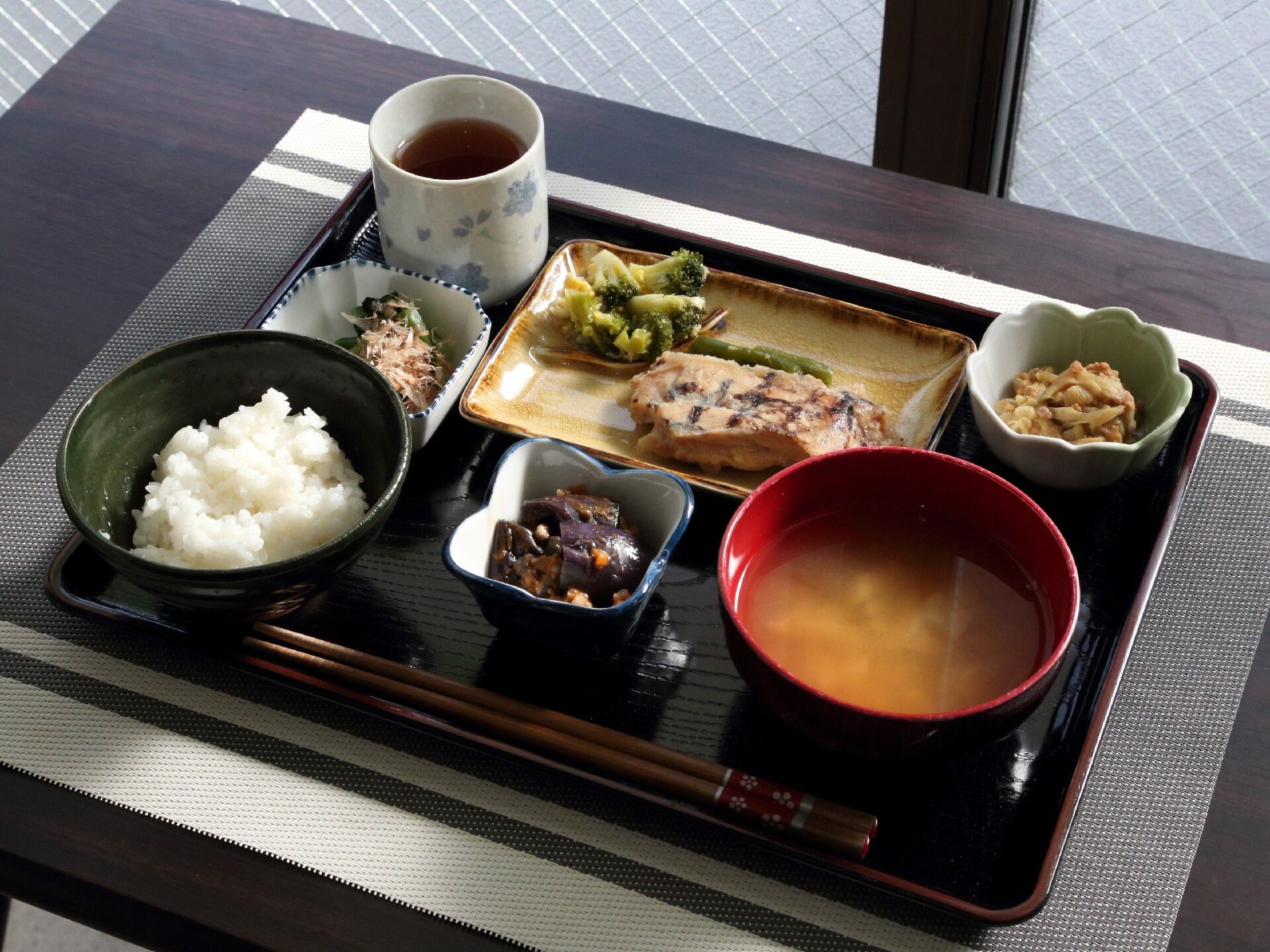 白米、みそ汁、小鉢、メインのおかず、お茶が乗ったトレー
