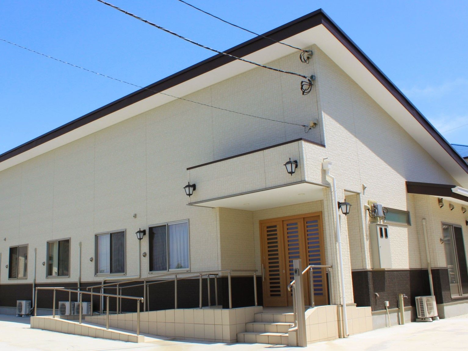斜めの屋根が印象的な施設の外観。木製ドアと白い壁が洋風と和風を融合している
