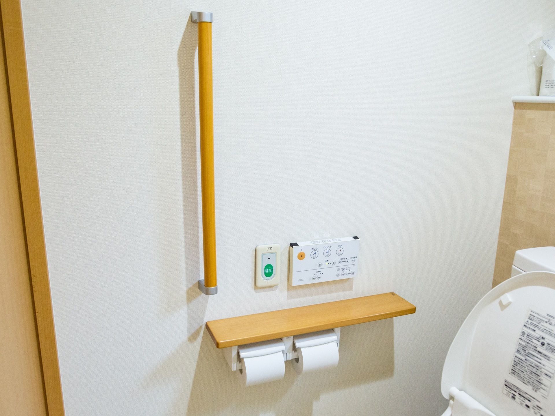 トイレの壁には、I字型の手すりやトイレットペーパー掛けが取りつけられている。そばには、たくさんのボタンも設置されている。