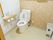 トイレは広々としており、白を基調とした清潔感のある内装となっている。壁には、トイレットペーパー掛けと手すりが設置されている。