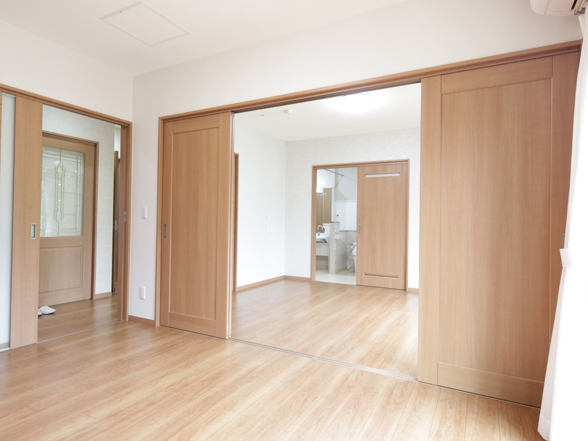 明るい色のフローリングの居室で、スライドドアで部屋を仕切ることができる。廊下もあり、ゆとりの広さである。