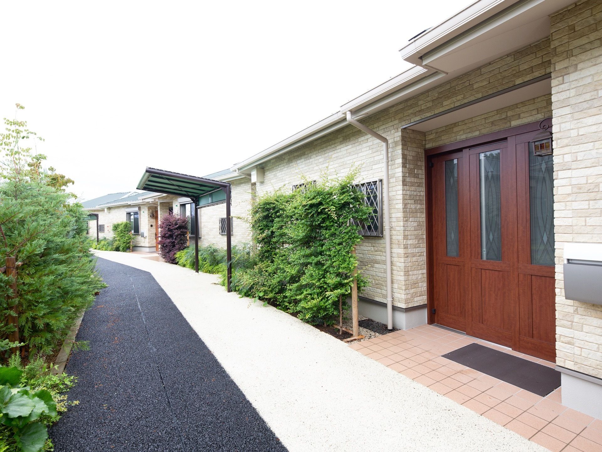 レンガ造りの平屋建ての建物が道路沿いに並んでいる。道路は二色に色分けされており、道路脇に木が植えられている。