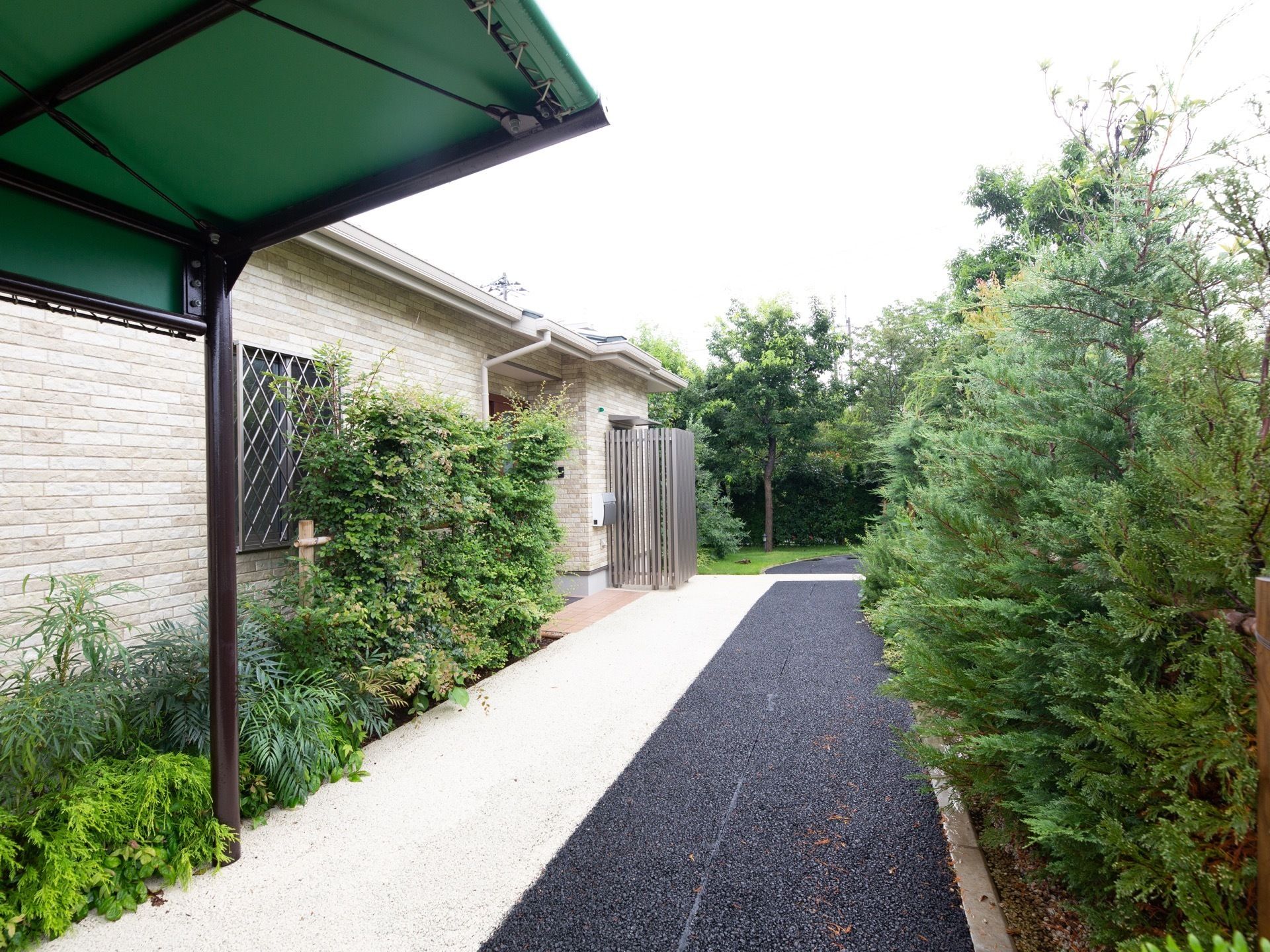 淡い色のレンガ貼りの外観の建物で、前の道路は白と黒に色が分かれている。道路沿いには緑が多く、落ち着いた雰囲気である。