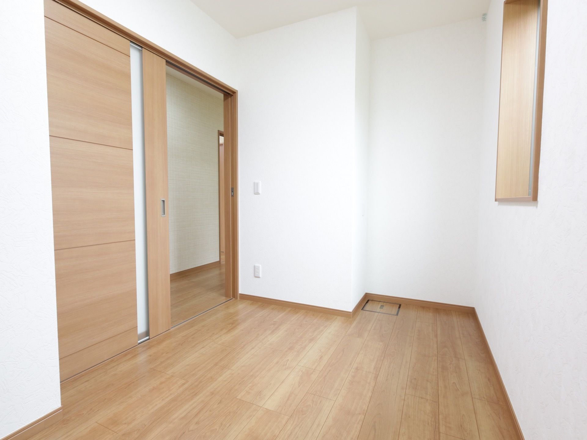 ナチュラルな雰囲気の住居内の小部屋である。窓が設置され、廊下と繋がる入り口は幅のある大きな引き戸になっている。