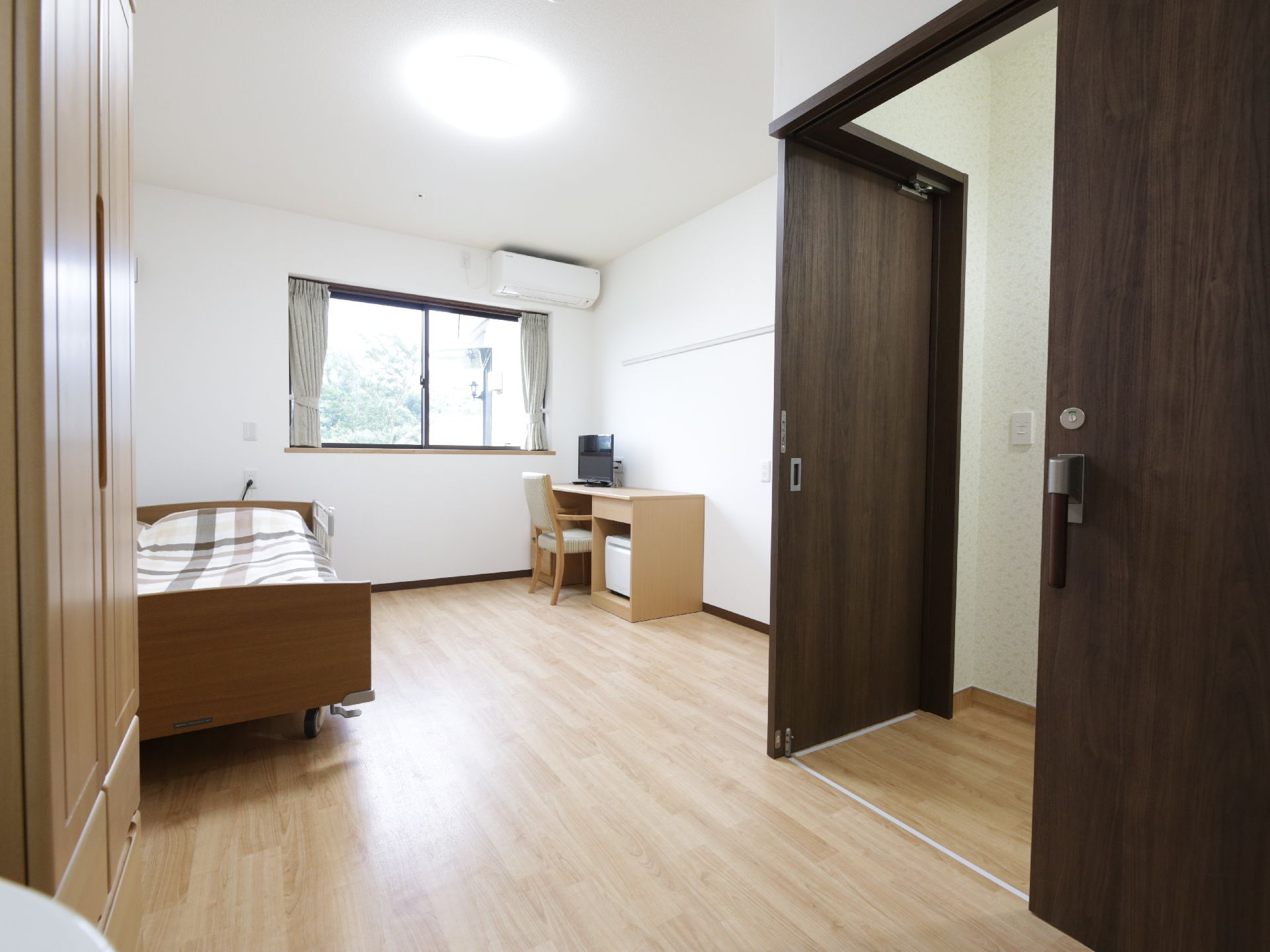 ベージュのテーブルと椅子、ベッド、エアコンがあるお部屋