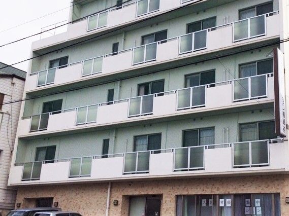 各フロアにベランダがついた大きな白い建物。1階部分はレンガ調の外壁。