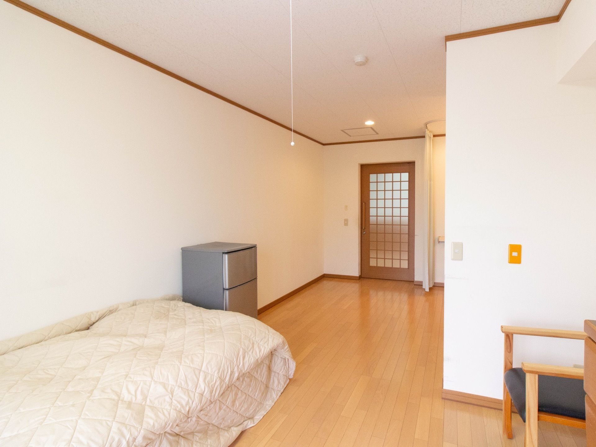 白を基調とした明るい清潔感のある居室である。ゆったりとした空間に介護用ベッドや椅子、冷蔵庫が完備されている。