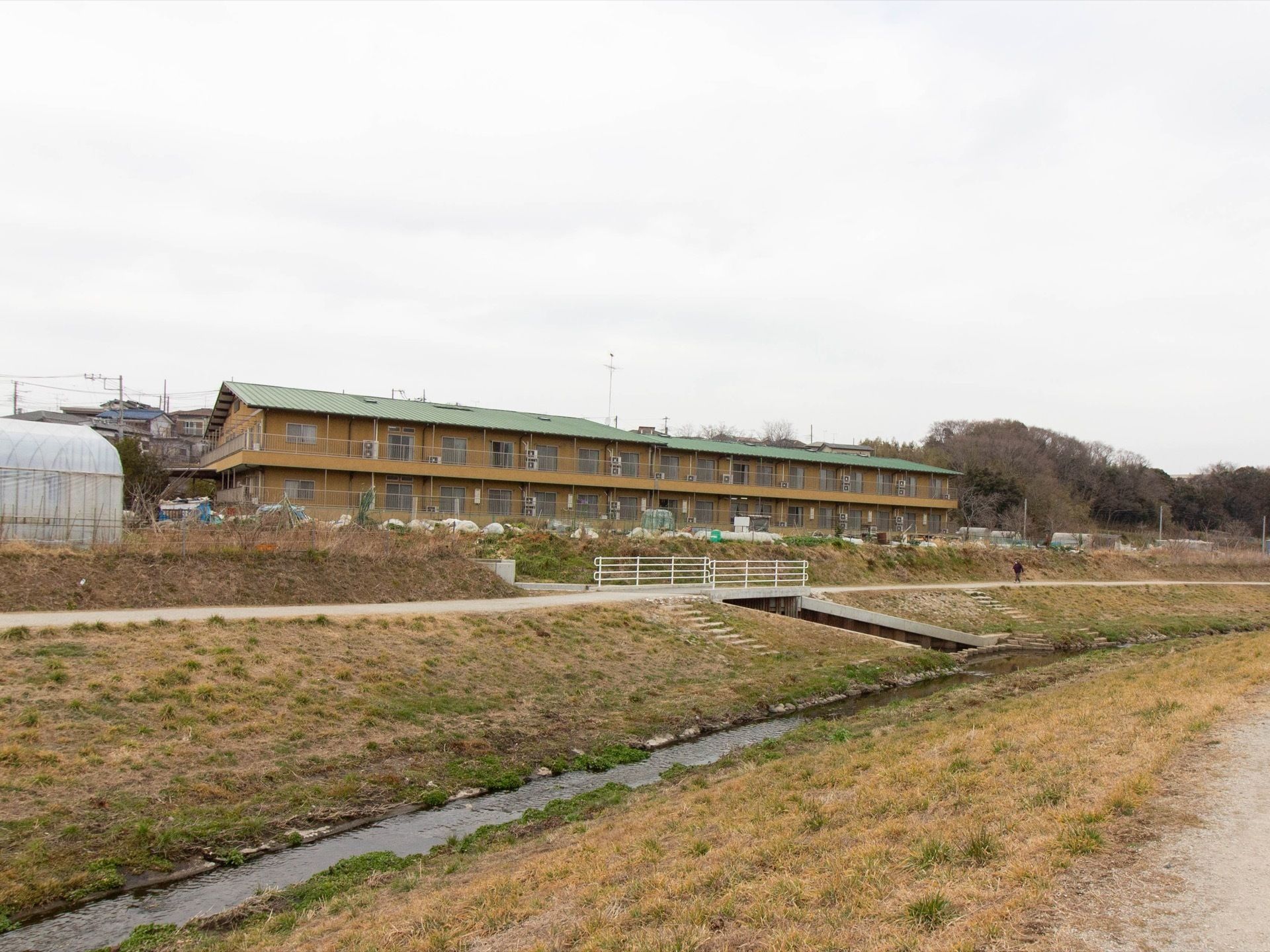 ベージュ色の外壁で、２階建ての大規模な建物である。ベランダが完備されている。周辺は自然に囲まれた静かな立地である。