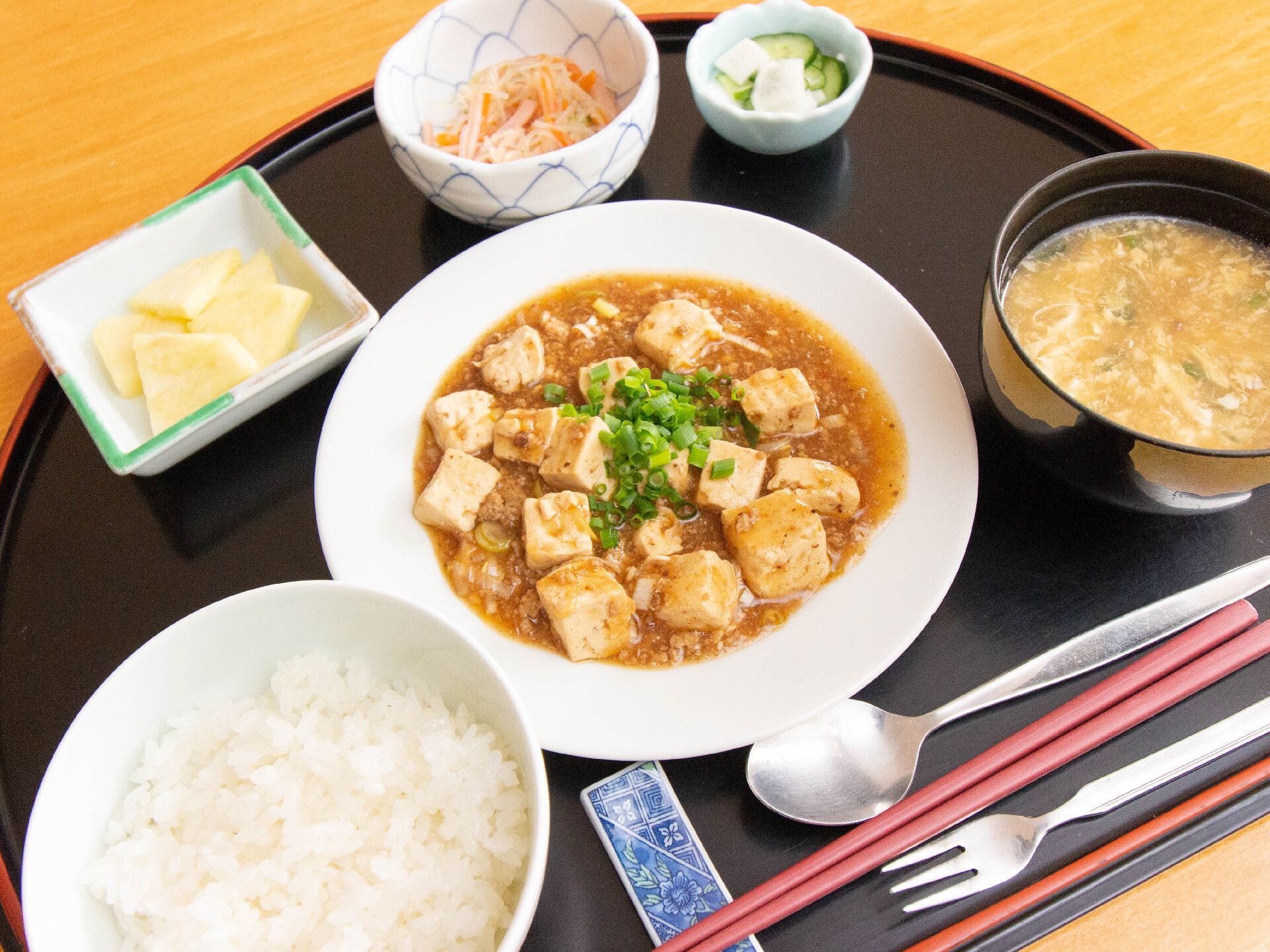 白米、麻婆豆腐、中華スープ、漬物、小鉢が乗せられているトレー