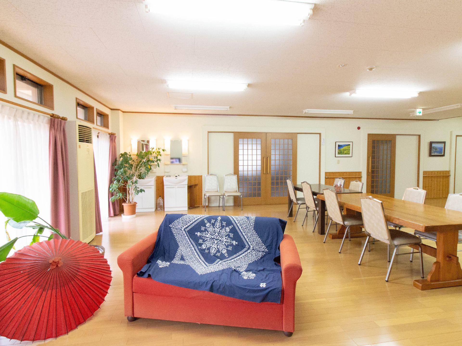 赤い番傘と青い布がかかった赤いソファが置いてある共有スペース