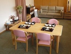 手前にリビングテーブルとイスがあり、奥のほうにソファやテレビがある一室の様子