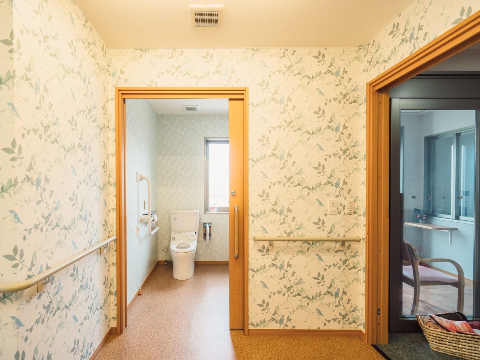 トイレへと続く廊下は、白地に緑鮮やかな枝や小鳥が描かれた壁紙が使用されている。落ち着いた中に高級感があり、印象的になっている。