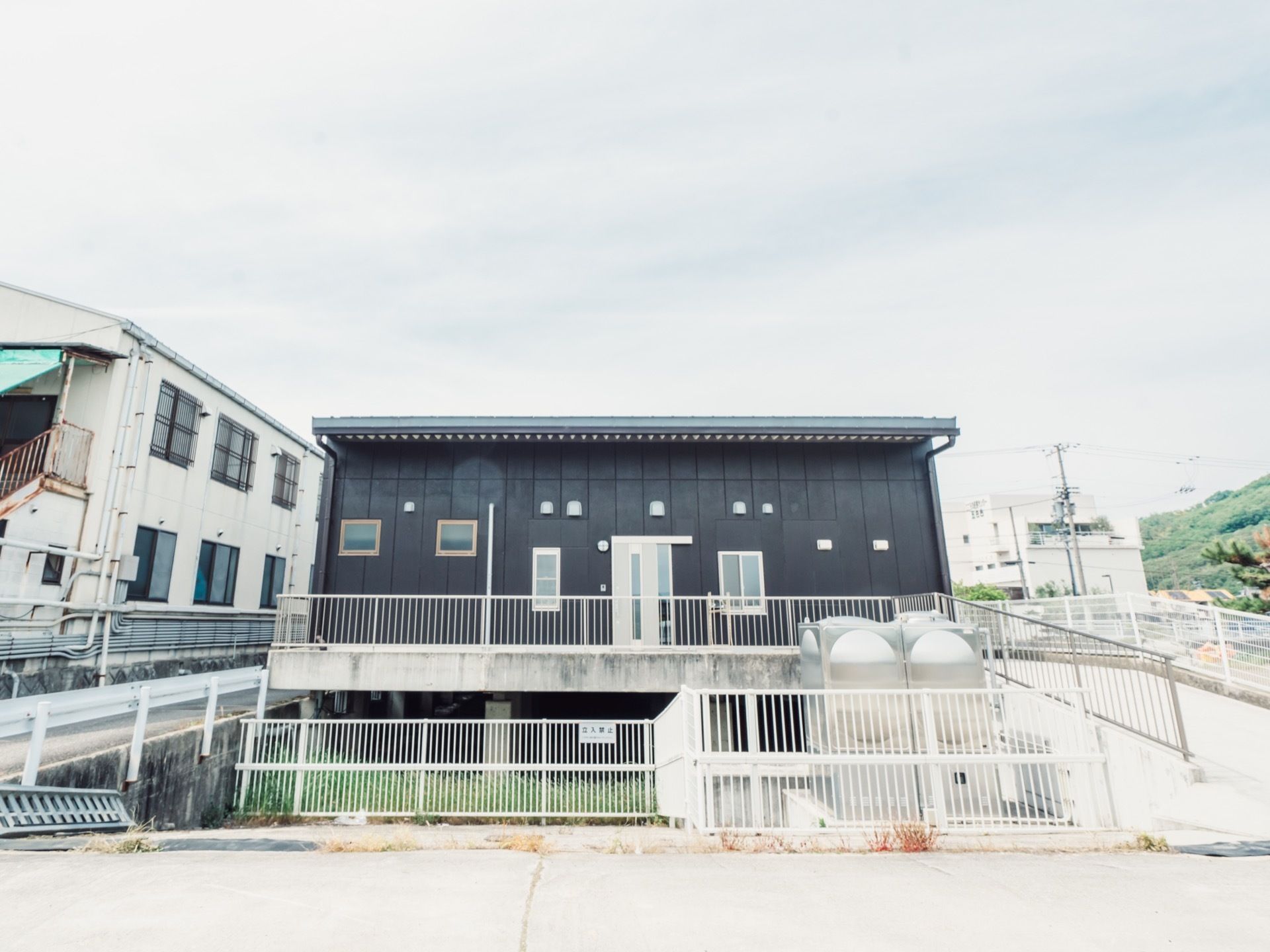 黒い外装が印象的な、平屋建ての建物。駐車スペースからエントランスまでは緩い傾斜のスロープが設置されている。