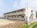 ２階建ての施設で、周囲は住宅地に囲まれている。施設の前は空き地になっており、たくさんの草が生えている。