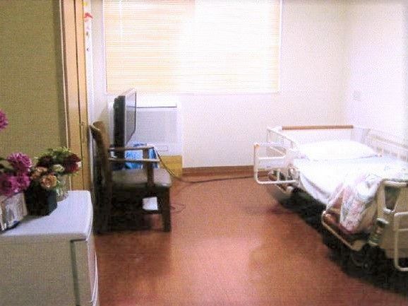 介護用ベッドやテレビ、ヒーターや冷蔵庫が置かれた居室。