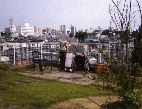 建物屋上の庭園から街を見下ろしている３人の人物。