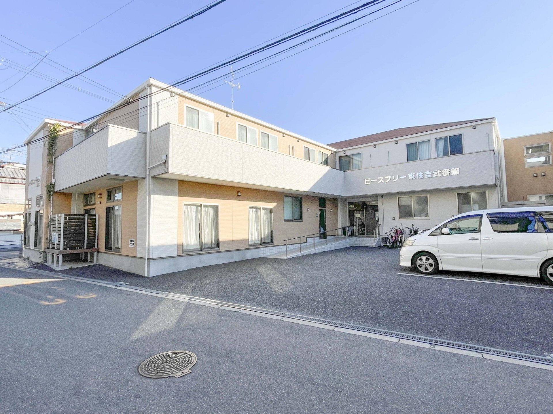車いすに乗った女性を押す家族の男性とそこに寄り添う介護スタッフの様子