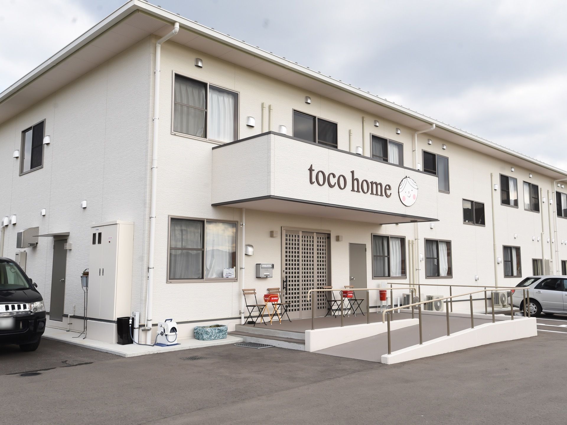 施設玄関へは、階段かゆるやかなスロープを使って向かえる。ドアの左右には喫煙用の吸い殻入れが置いてある。