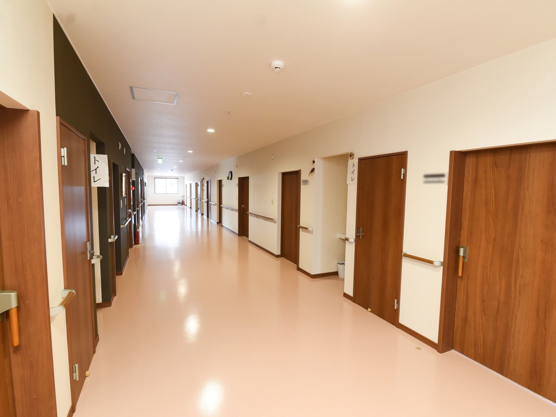 廊下は幅が広々としている。壁や床、天井は白で統一されており、ドアや手すりの木目調がアクセントになっている。