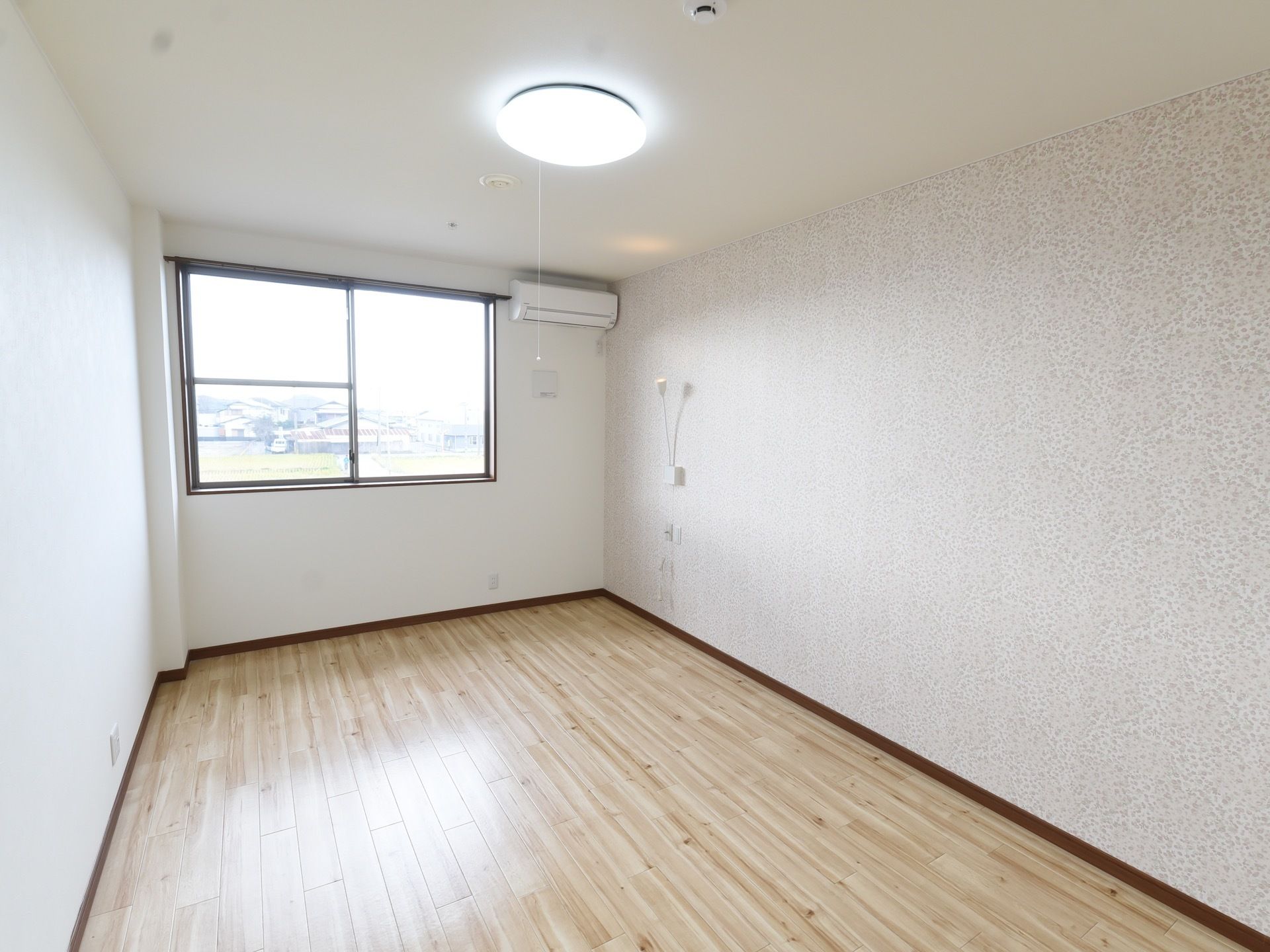 居室はシンプルなつくりになっている。照明やエアコンが完備されており、窓からは閑静な住宅街の様子が見られる。