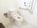 タイル張りの明るい広々としたトイレに、蓋がついていない洋式便器が据えられている。便器の左右に、ステンレス製のグリップがある。