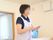 メモを片手に入居者様に話しかける女性スタッフの様子。レクリエーションなどで使用するリングを片腕に掛けている。