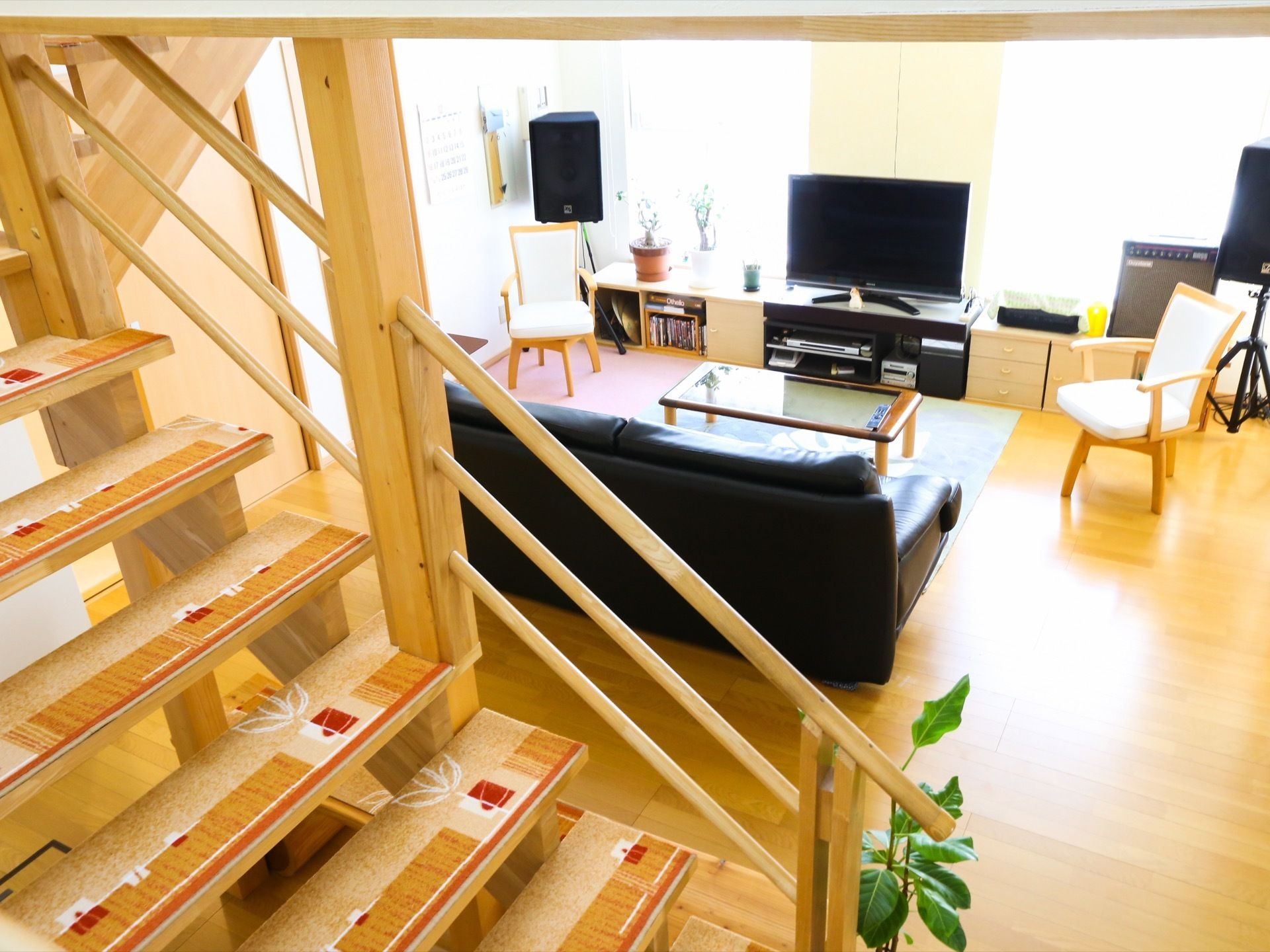 木のぬくもりを感じる居間である。ソファーやテーブル、椅子、大きなテレビが置かれている。観葉植物もある。