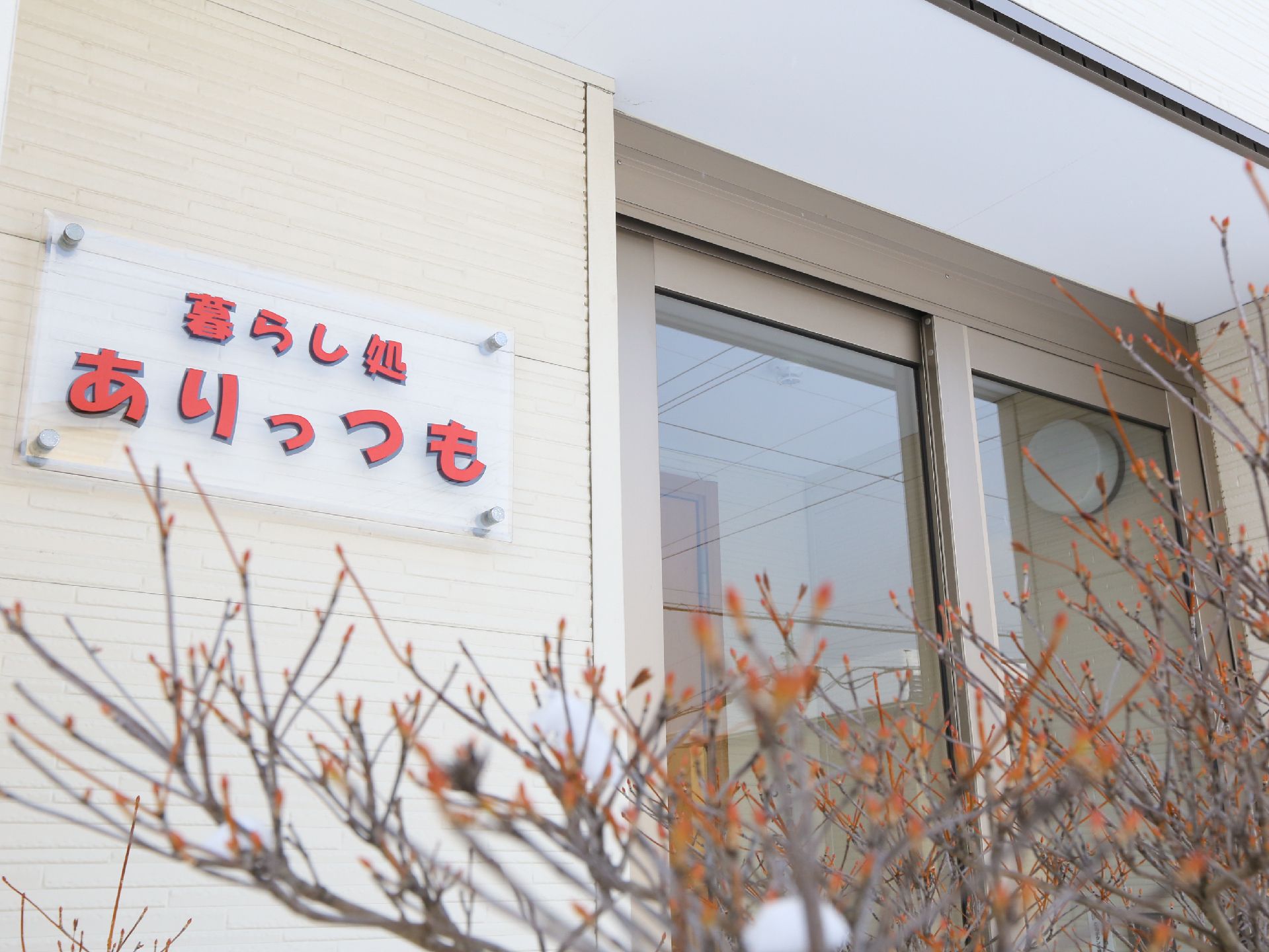 介護施設の名前が書かれている看板と、自動ドアの玄関