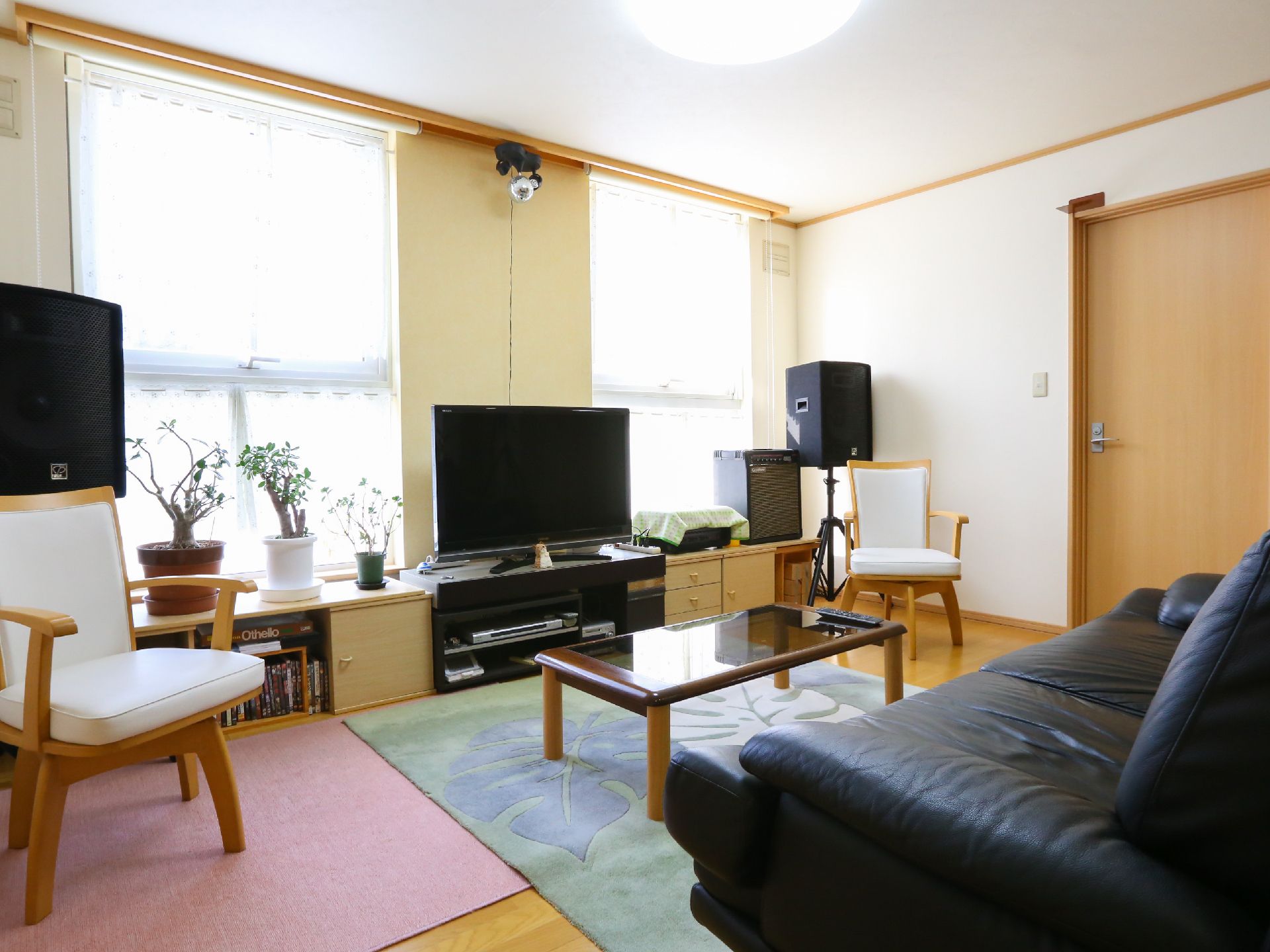 黒いソファとローテーブル、白い椅子とテレビがあるお部屋