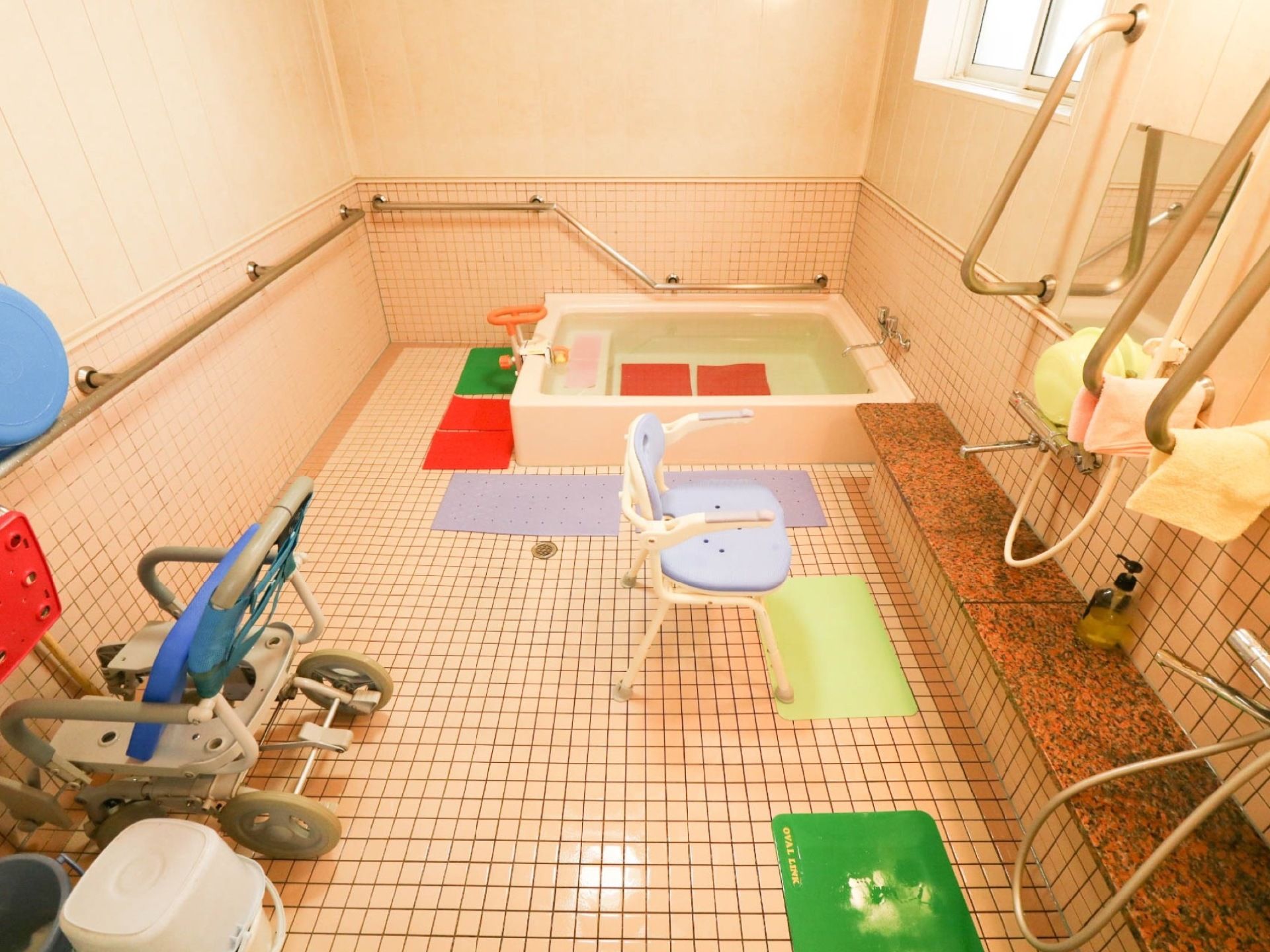 床と壁はタイル張りになっている。洗い場には背もたれ付きのシャワーチェアが置かれている。床には滑り止めマットが敷かれている。