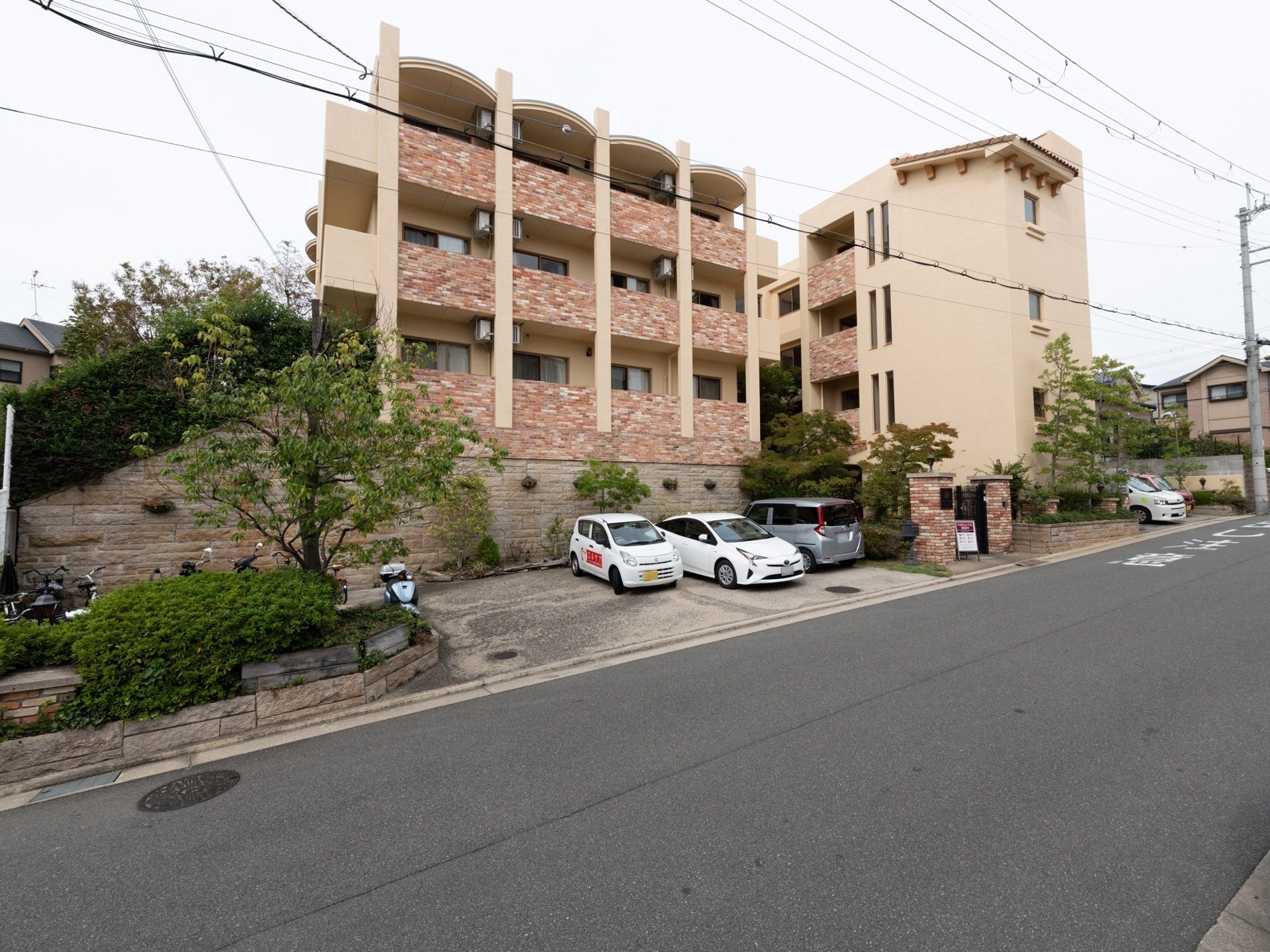 駐車スペースを完備した勾配ある道路際に立地する３階建て施設