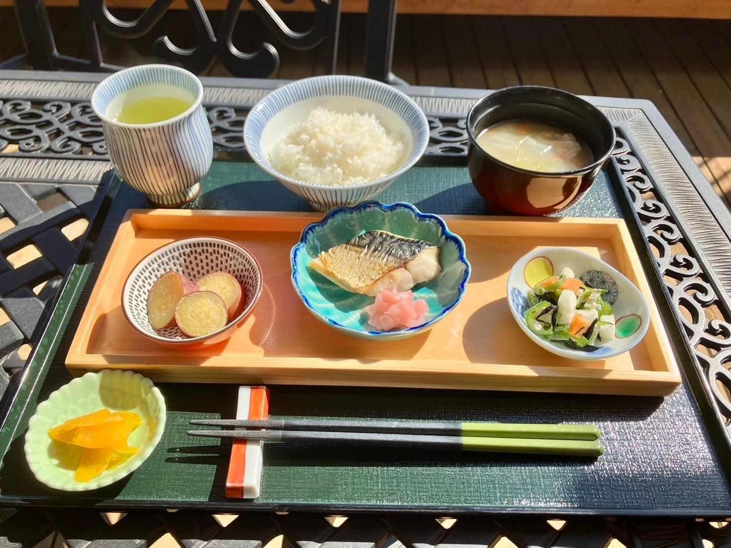 マグロととろろ芋の乗ったどんぶりと、野菜やきのこの料理が小鉢に盛り付けてある