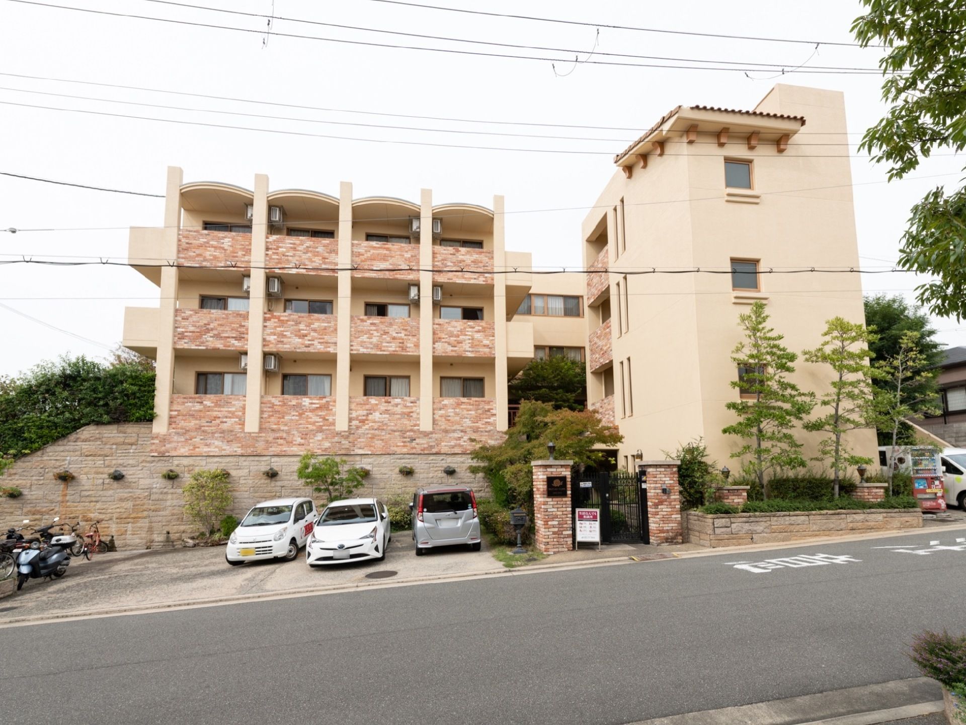 施設の建物と車道の間に、複数台の車を置ける駐車場が備わっている。門の前には分かりやすく看板が立てられている。