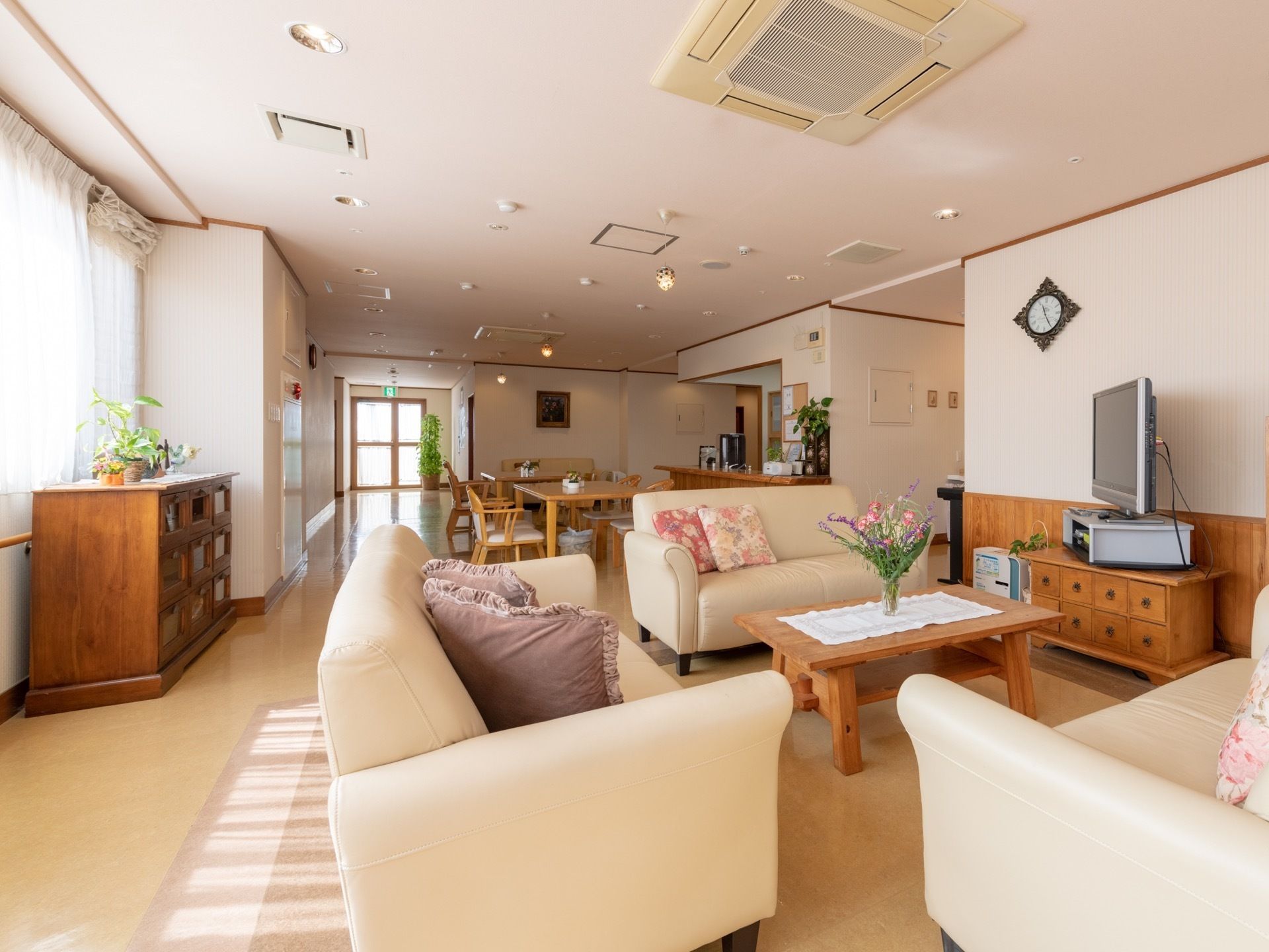 リビングは清潔感のある白壁に、あたたかみのある木製の家具がたくさん配置されている。テーブルにソファ、サイドボード、テレビなどが設けられている。