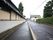 施設周辺には、しっくい塀が続いている道路がある。道路をはさんだ所には、木が並んでいる垣根があり、その内側に大きな松の木が生えている。