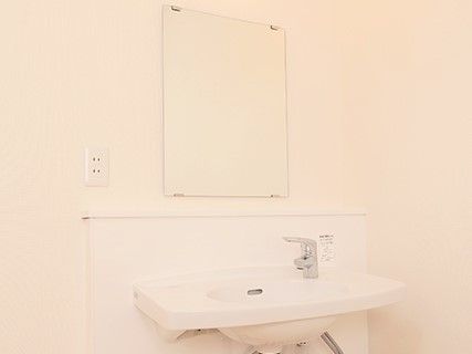 鏡やコンセントの差し込み口が設置された洗面スペース。蛇口はひねらなくても水が出るタイプ。