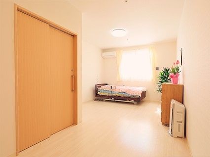 ベッドやたんす、エアコンなどが設置されたフローリングの居室。