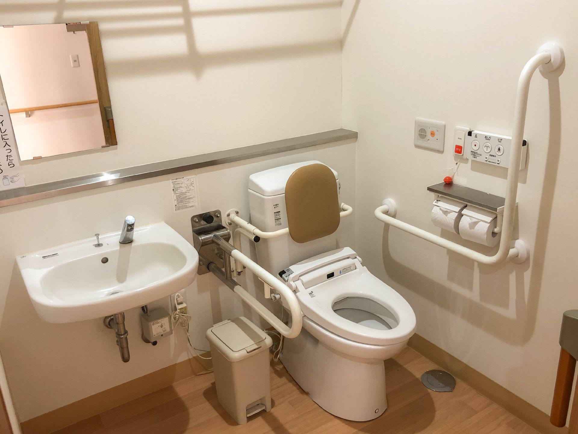 背もたれや手すりが付いた便座にはふたがなく、トイレ内のスペースはとても広い。手洗い場も付いている。