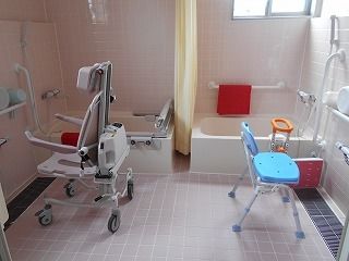 二つの個浴槽が設置された広い浴室。左側の浴槽にはレールが付き、車いすタイプのリフトもある。