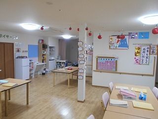 たくさんの飾りつけがされた共有スペースにはピンクの椅子がセットされた木製のダイニングテーブルが多く置かれている。