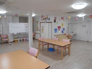はっぴや提灯の絵が飾られた館内には木製のダイニングテーブルが複数置かれ、明るい雰囲気。