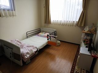 寝具付きのベッドやタンスなどが置かれたフローリングの部屋には、大きな窓が二つ付いている。