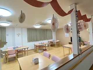 ブラウンのリボンや紙の飾りが飾られた食堂。カーテンが付いた大きな窓があり、テレビやダイニングテーブルが置かれている。
