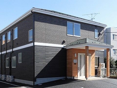 2階建ての建物は黒く、スタイリッシュなデザイン。玄関には白いドアが付き、屋根も設置されている。